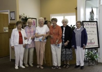 A group of elderly standing in front of an apartment building, smiling and holding keys.