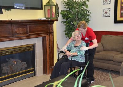 A caregiver assisting a woman in a wheelchair.