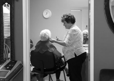 An elderly woman at a salon getting her hair cut by another woman.