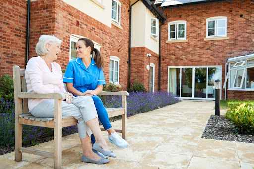 A woman seated on a bench engaged in a conversation with a nurse