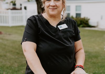 A woman in a black shirt with orange standing next to a cart.