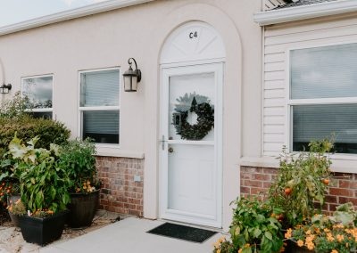 A charming outdoor home adorned with potted plants and a welcoming door.