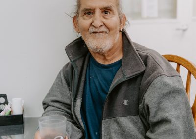 An elderly man enjoying a cup of coffee at a table.