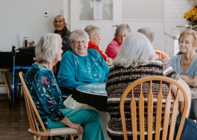 A group of elderly enjoying a meal together at a dinner table, engaged in conversation and laughter.